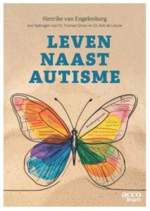 Cover van "leven naast autisme' Met een kleurige vlinder met tekst erin op een ondergrond van zand